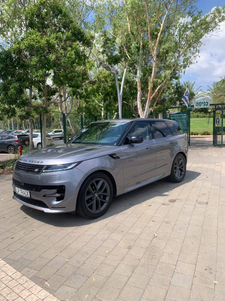 לנדרובר ריינג' רובר כסוף, חזית הרכב, חניה ליד עצים ושער הפארק.